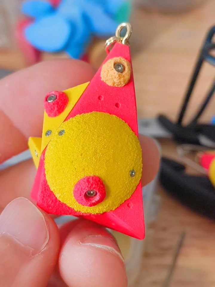 Red triangular miniature climbing volume with a large yellow round hold and small red holds